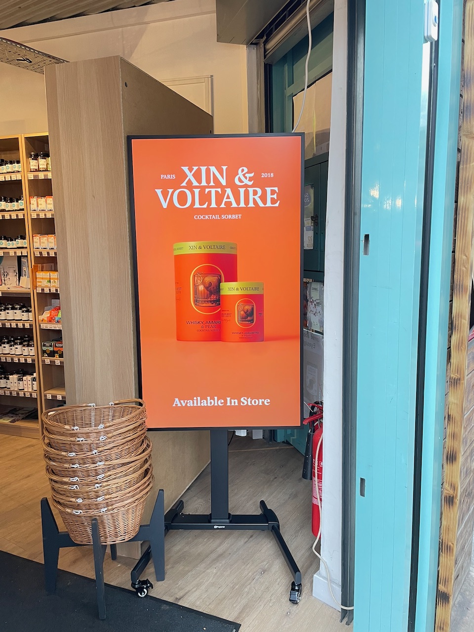 Hanei freestanding screen running a Xin & Voltaire cocktail sorbet campaign in an independent health food store